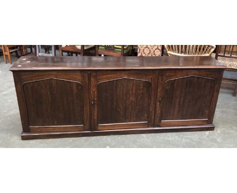 A low oak cabinet comprising three panel doors, opening to an interior of pigeonholes, one door locked, 195x34x72cmH 