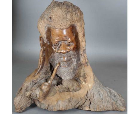 A large late 20th century African carved root sculpture of a man's head with pipe, height 80cm, width 94cm.
