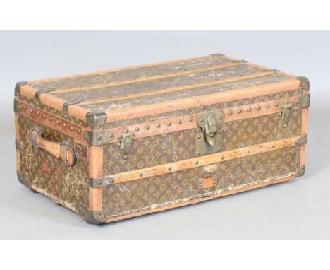 An early 20th century Louis Vuitton travelling trunk with overall monogram canvas covering and tan leather strapping, the int