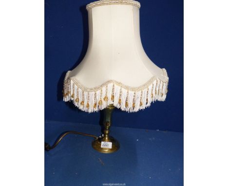 A brass candlestick converted to an electric table lamp, with tasselled and beaded shade.