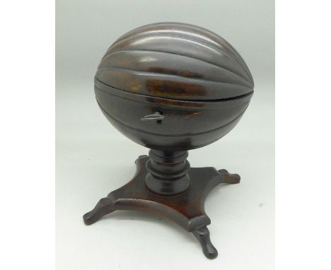 A carved coconut caddy on a mahogany pedestal
