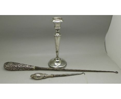 A silver candlestick and two button hooks