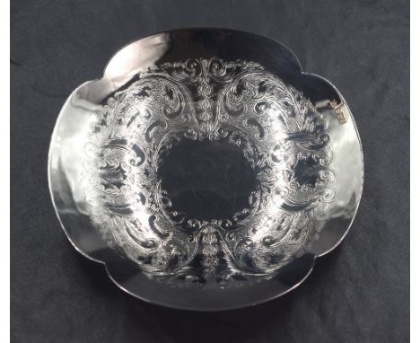 An Elizabeth II silver dish, of quatrefoil lobed form with decorative scroll engraving to the bowl, raised on a circular step