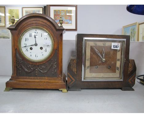 An EArly XX Century Oak Mantel clock, with arched top brass finial's, enamel dial, to swag ribbon decoration on gilded brass 