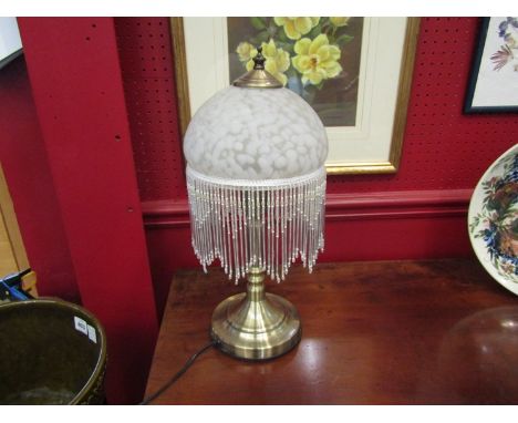 A bronzed base table lamp with mottled and tasseled shade 
