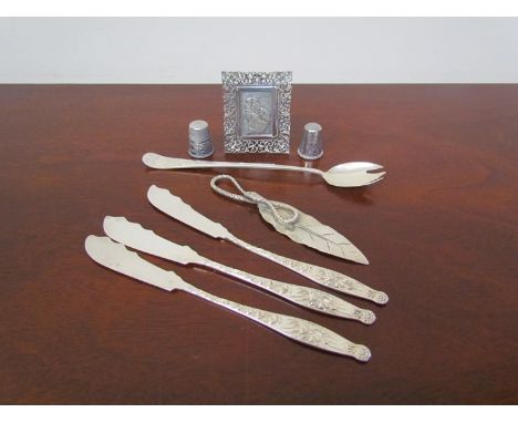 A silver pickle fork, sterling butter knives, sterling page marker with snake detail, thimbles and miniature picture of Mary 