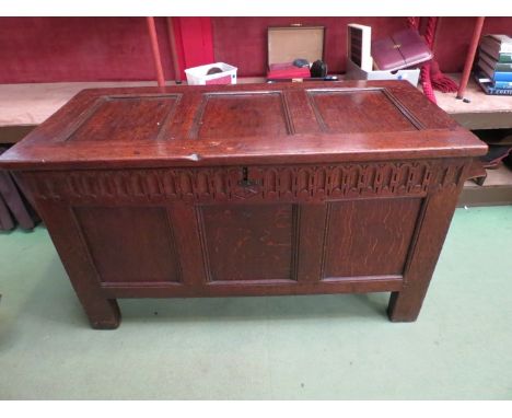 Circa 1680 a pegged oak three panel coffer with lidded internal candle box the hinged top over a carved frieze on stile feet 