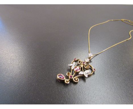 A gold chain hung with ornate diamond and ruby set pendant of heart form, stamped 9k