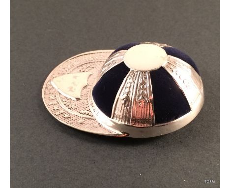 A silver pin cushion in the shape of a cap