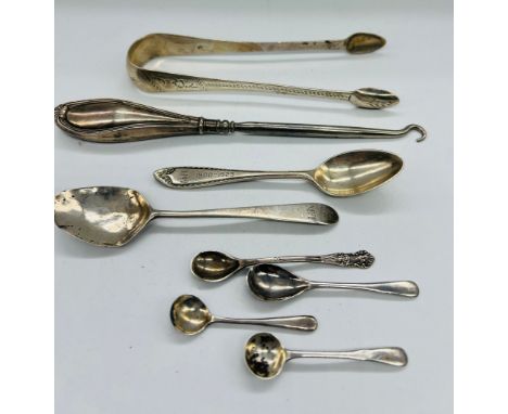 A selection of hallmarked silver items to include teaspoons, mustard spoons, sugar tongs and a silver handled button hook. Va