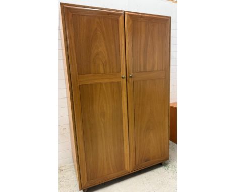 An Ercol style double wardrobe opening to hanging rail and shelf to top (H187cm W124cm D66cm)