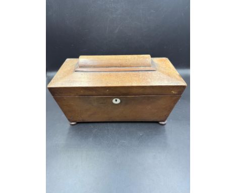 A mahogany tea caddy in the sarcophagus form with two compartments flanking a glass mixing bowl 