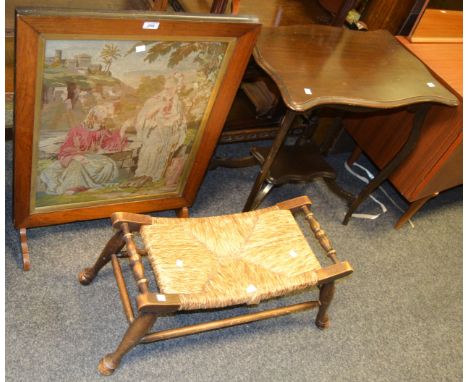 A Victorian tapestry firescreen depicting a religious scene; an oak rush footstool with turned supports; a shaped rectangular