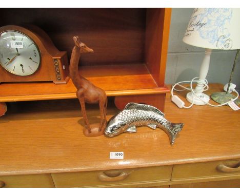 A carved wooden figure of a giraffe together with a ceramic silvered fish