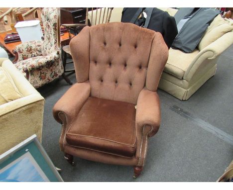 A brown button back wingback armchair