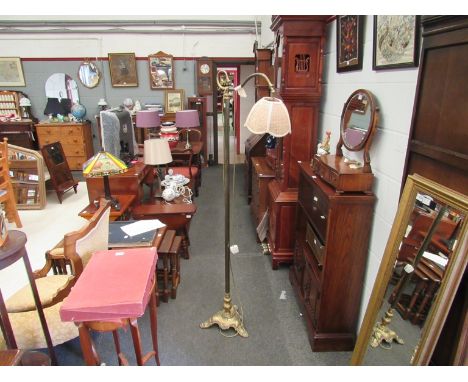 A Victorian brass standard lamp with crooked and scrolled arm joining a shade, on lion paw plateau base  