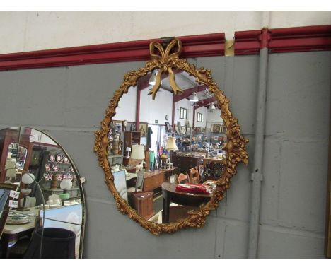 A gilt framed oval mirror with ribbon and swag frame, 57cm x 48cm overall