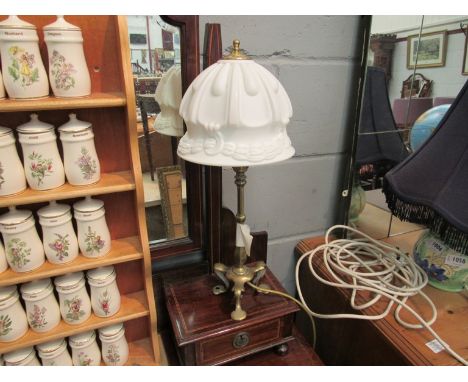 An early 20th Century brass table lamp with milky glass shade over foliate tripod base