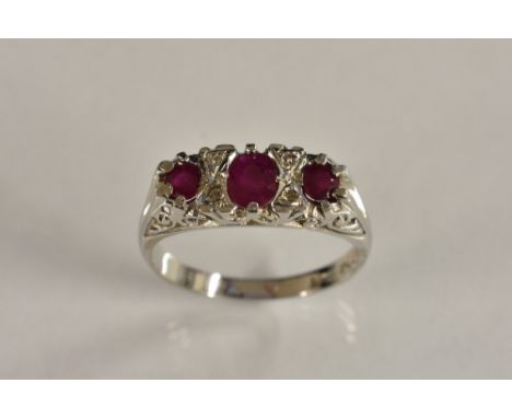 A diamond and red spinel seven stone panel ring, three graduating pinky red spinel's, each divided by a pair of diamond accen