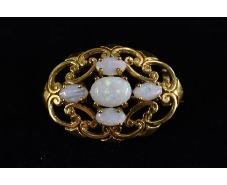 An oval five stone opal brooch, five creamy white opal doublets flashing red, blue green and orange play, 9ct gold scrolling 