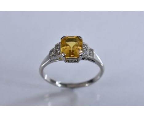 An Art Deco yellow stone and diamond ring,  central cushion cut yellow stone, quarter claw set, above tapering diamond accent