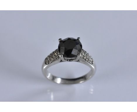 A black and white diamond ring, central black round cut diamond quarter claw set above white diamond encrusted tapering shoul