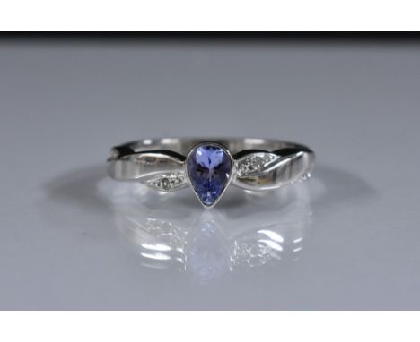 A tanzanite and diamond ring, pale purple pear drop tanzanite collet set between diamond accented shoulders, 9ct gold white s
