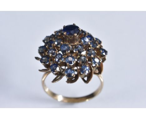 A blue spinel and gold coloured metal conical pyramid four tier dress ring, yellow metal shank, stamped 14k, size, O, 5.1g gr