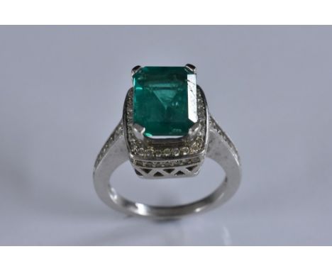 A emerald and diamond ring, central emerald cut emerald measuring approx 11 x 8.3 x 6.5mm calculated weight approx 3.5ct, sur