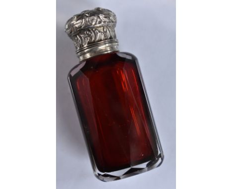 A 19th century silver mounted ruby glass faceted scent bottle, hinged cover chased with scrolling foliage and enclosing a sto