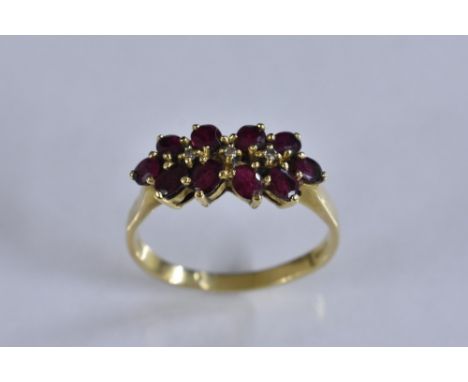 A ruby and diamond cluster ring,  central line of three individually set diamond accents, surrounded by a band of ten red rub