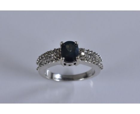 A sapphire and diamond ring, central oval blue/green sapphire approx 1.0ct, quarter claw set above baguette and round cut dia