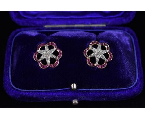 A pair of diamond and ruby six point star earrings, encrusted with diamonds, within a shaped ruby encrusted surround, unmarke