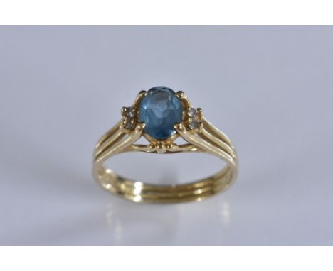 A topaz and diamond ring, central oval blue topaz, flanked either side by a pair of diamond accents, 14ct gold shank, stamped