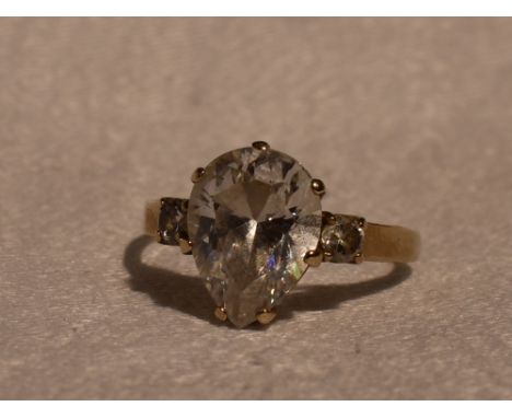 A lady's dress ring having a teardrop cut cubic zirconia flanked by a round cut CZ to each shoulder on a 9ct gold loop, size 