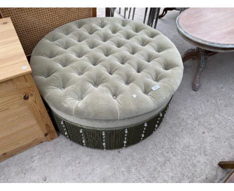 A GREEN BESPOKE MADE BUTTON TOP CIRCULAR OTTOMAN WITH CRYSTAL FRINGING.THIS IS MADE FROM EXPENSIVE FABRIC AND WAS MADE AT A C