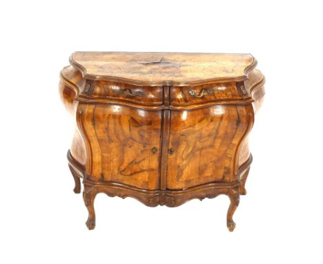 A 19th Century Italian walnut bombe shaped commode / cabinet, the serpentine top above two short drawers with cupboard below 