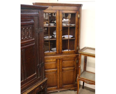 A Georgian design oak corner cabinet,&nbsp;the upper shaped shelves enclosed by glazed panel doors, shelves below enclosed by
