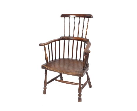 An 18th Century rustic elm seated comb back elbow chair, the shaped seat raised on baluster turned supports united by an H st