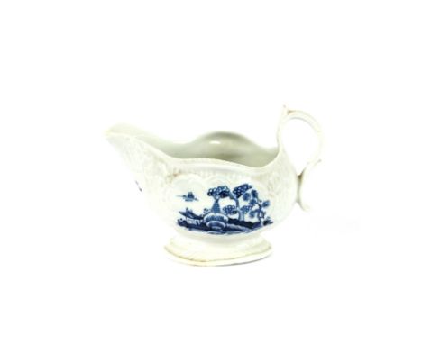 An 18th Century Worcester blue and white cream jug, decorated scenic panels and floral sprays on moulded leaf ground, scroll 