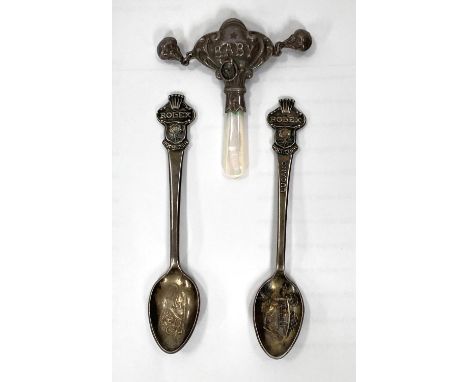 Two white metal Rolex Bucherer teaspoons with Rolex crown finials and a white metal and mother of pearl baby rattle stamped 9