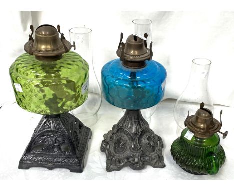 Two Victorian cast iron and coloured glass oil lamps and a smaller lamp 