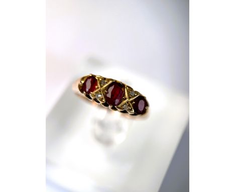 An 18 carat hallmarked gold ring set with 3 garnets and diamond chips, 5.5 gm, size L 