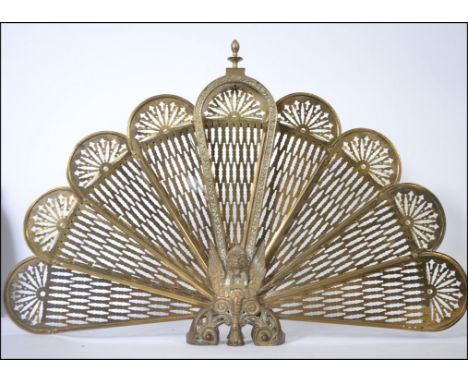 A 20th Century brass metamorphic peacock firescreen having eight fan out leaves with a Griffin base in working order with all