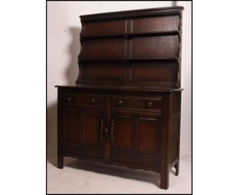 An Ercol dark Jacobean revival beech and elm dresser having cupboards and drawers to the base with plate rack atop. Measures:
