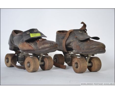 A pair of vintage mid century leather roller skates having wooden wheels to both skates L18cm