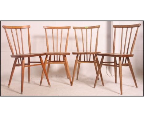A set of 4 Ercol beech and elm dining chairs having turned legs with upper peripheral stretchers, saddle seats and turned bac