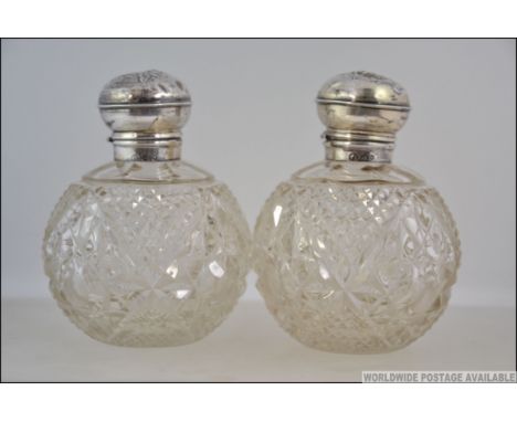 2 silver hallmarked and cut glass ladies perfume bottles. Each with decorative silver tops complete with stoppers. Hallmarks 