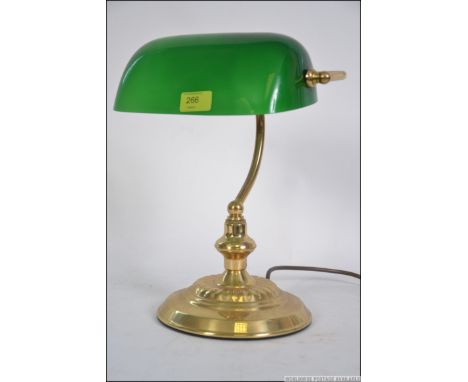 A 20th century bankers desk lamp having a green glass shade being raised  on a brass stand with. Measures: 33cms high.