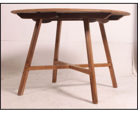 A 1970's retro beech and elm wood Ercol drop leaf dining table raised on squared angle legs with x-stretcher. Above a drop le